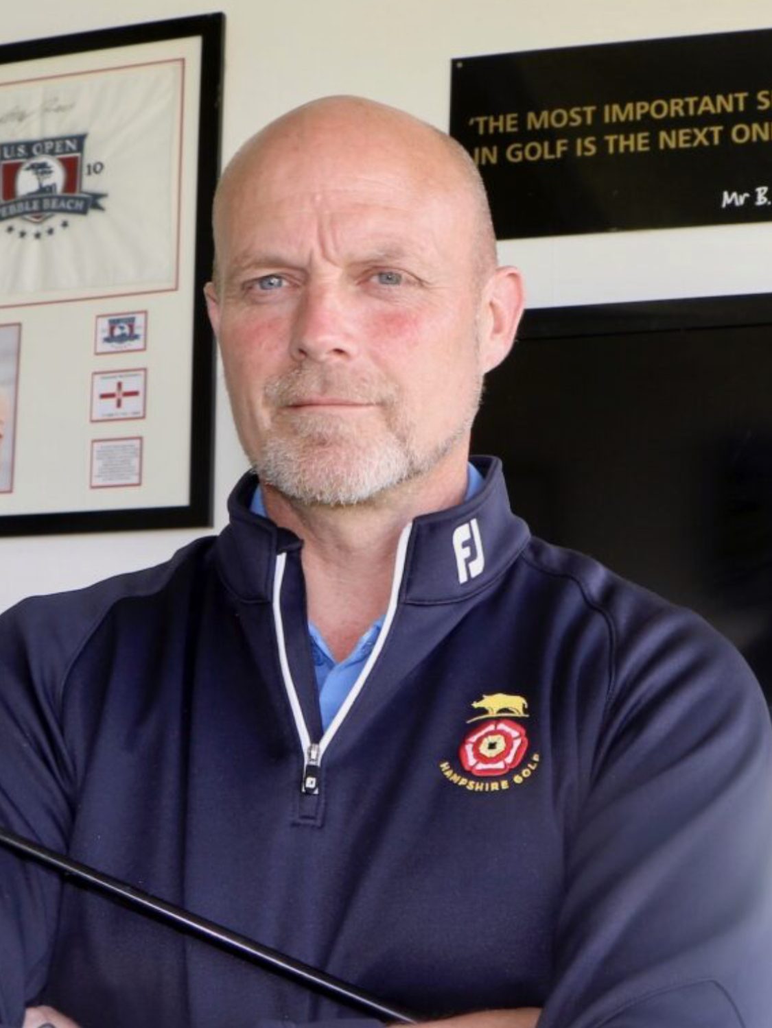 Man holding golf club in indoor setting.