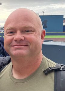 Smiling man at a sports stadium.